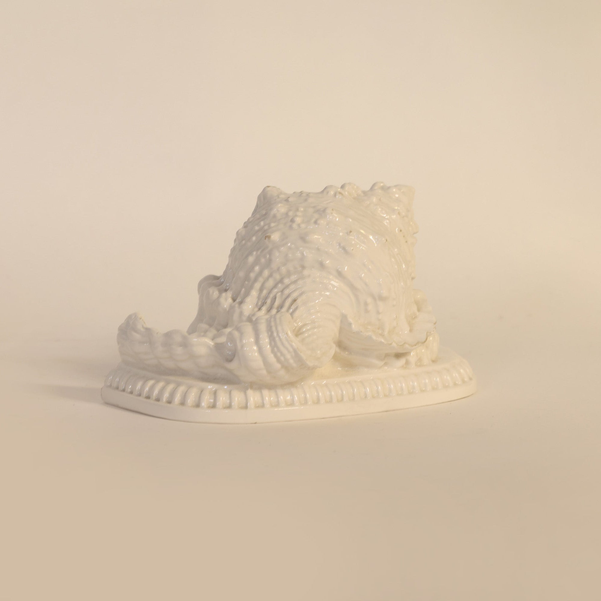 Sculptural vintage milk glass seashell on a beige background