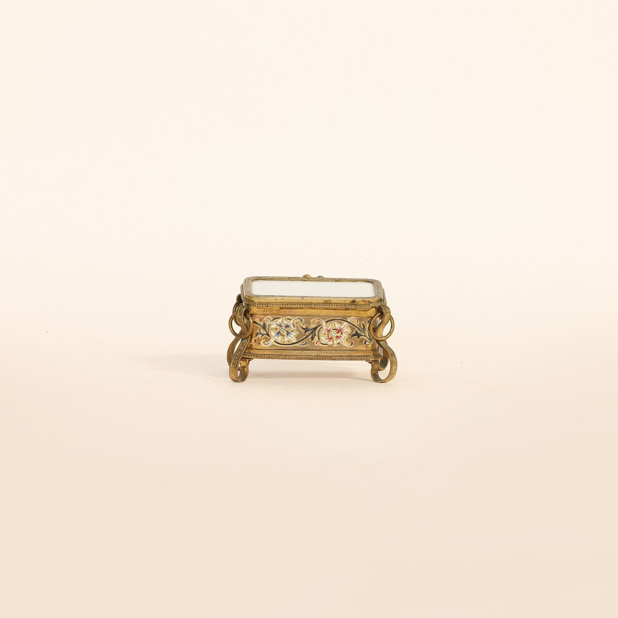 Small decorative gold box with gemstones on a beige background