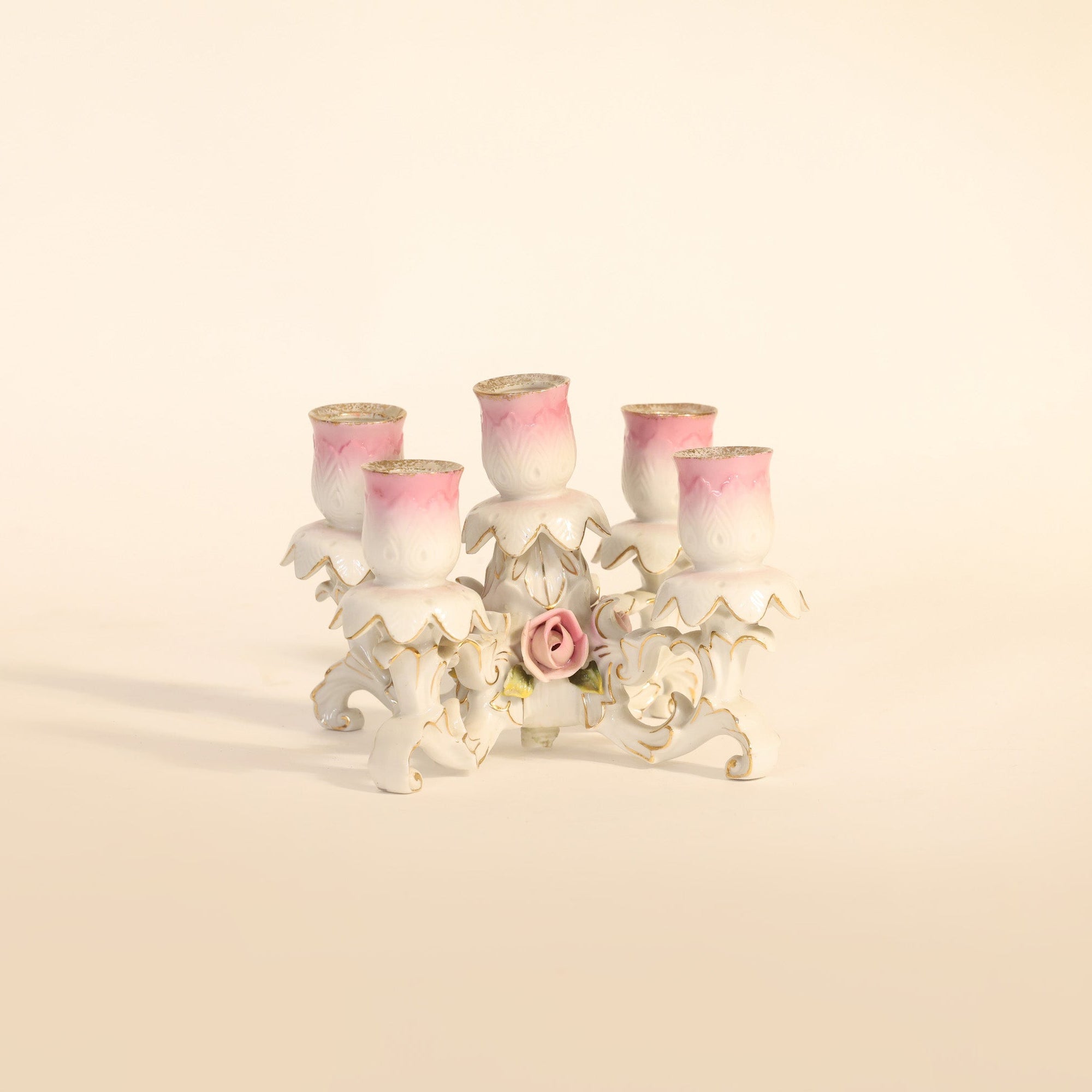 Decorative candle holder with four pink candles on a beige background