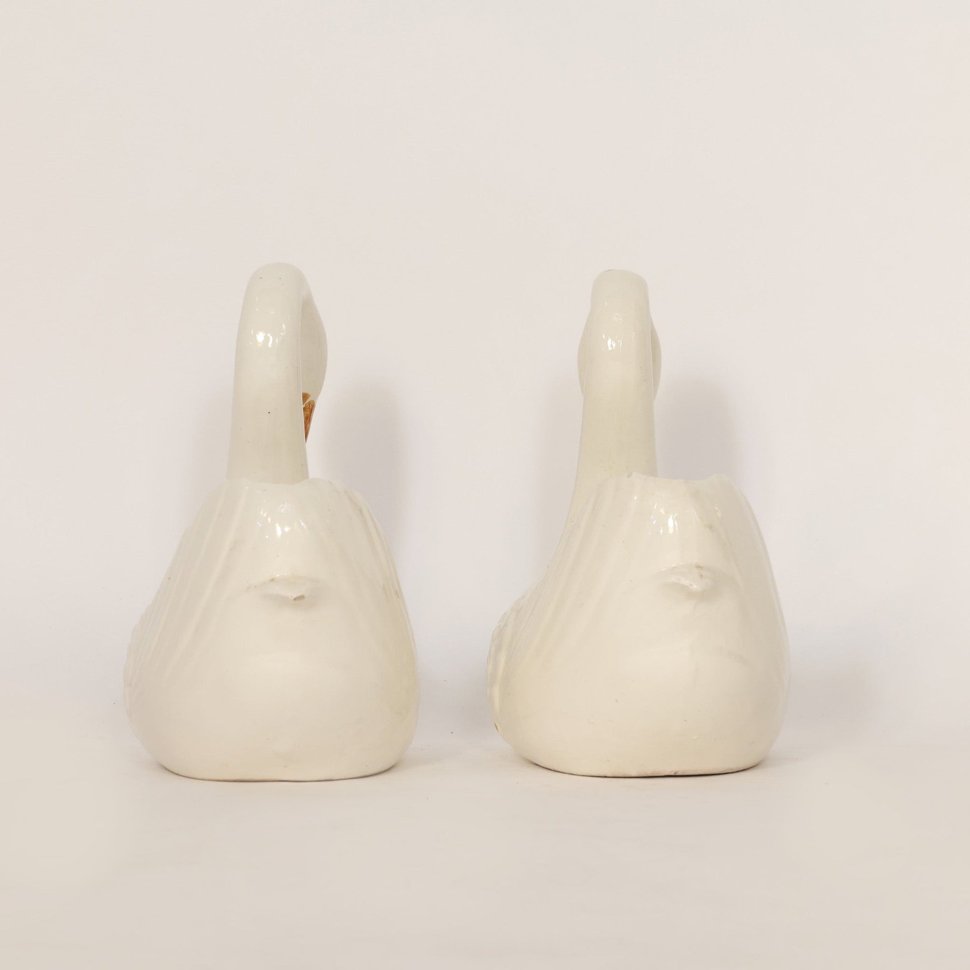 Two white ceramic swans on a light beige background