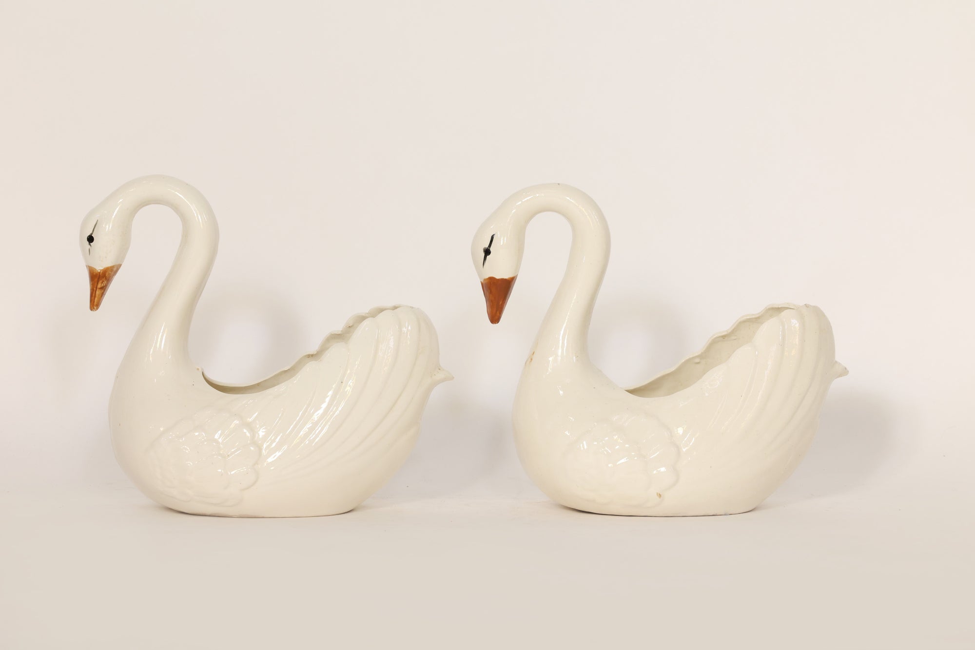 Two white ceramic swan-shaped ceramics on a light gray background