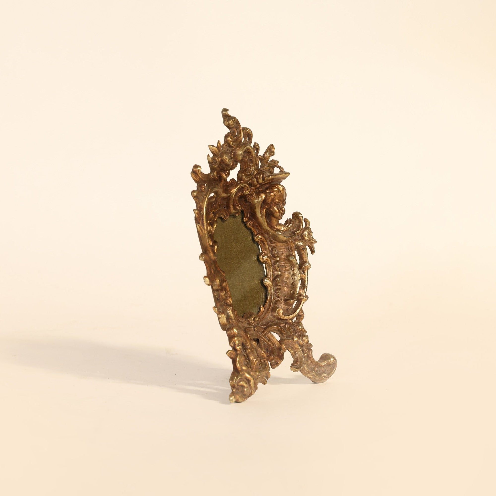 Decorative gold mirror with intricate designs on a beige background