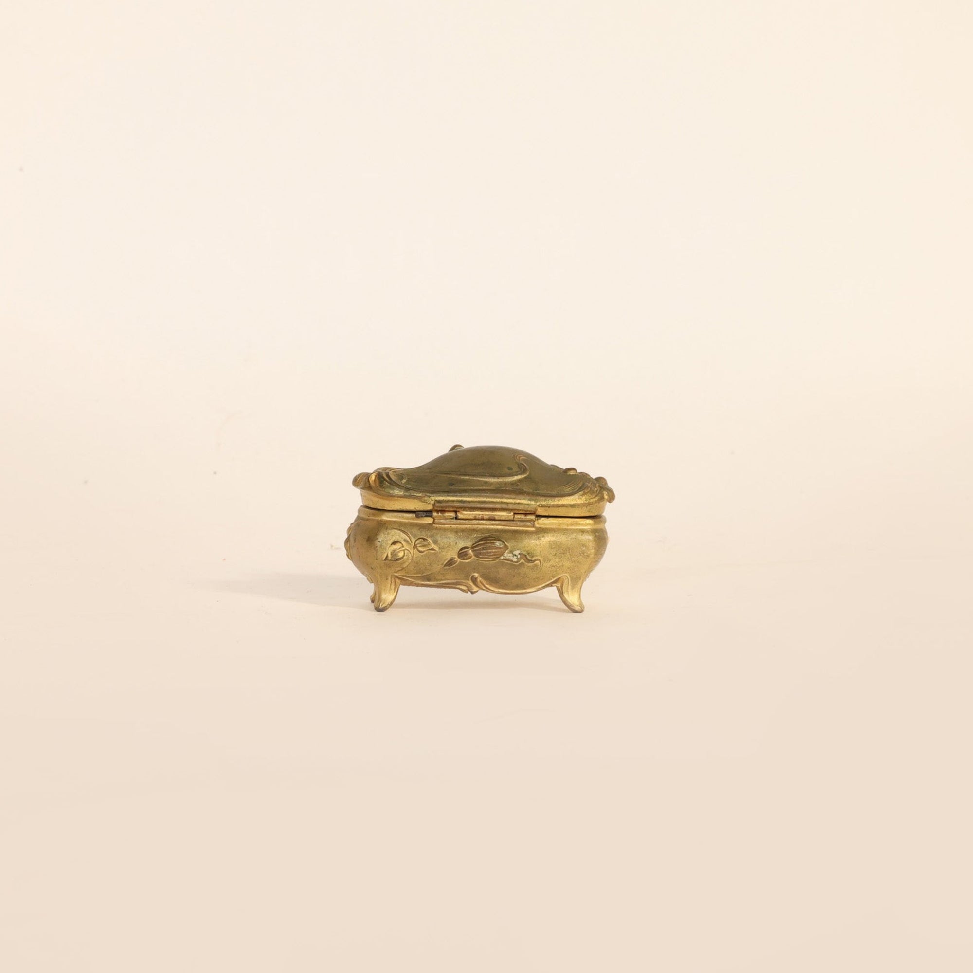 Small ornate brass box on a beige background