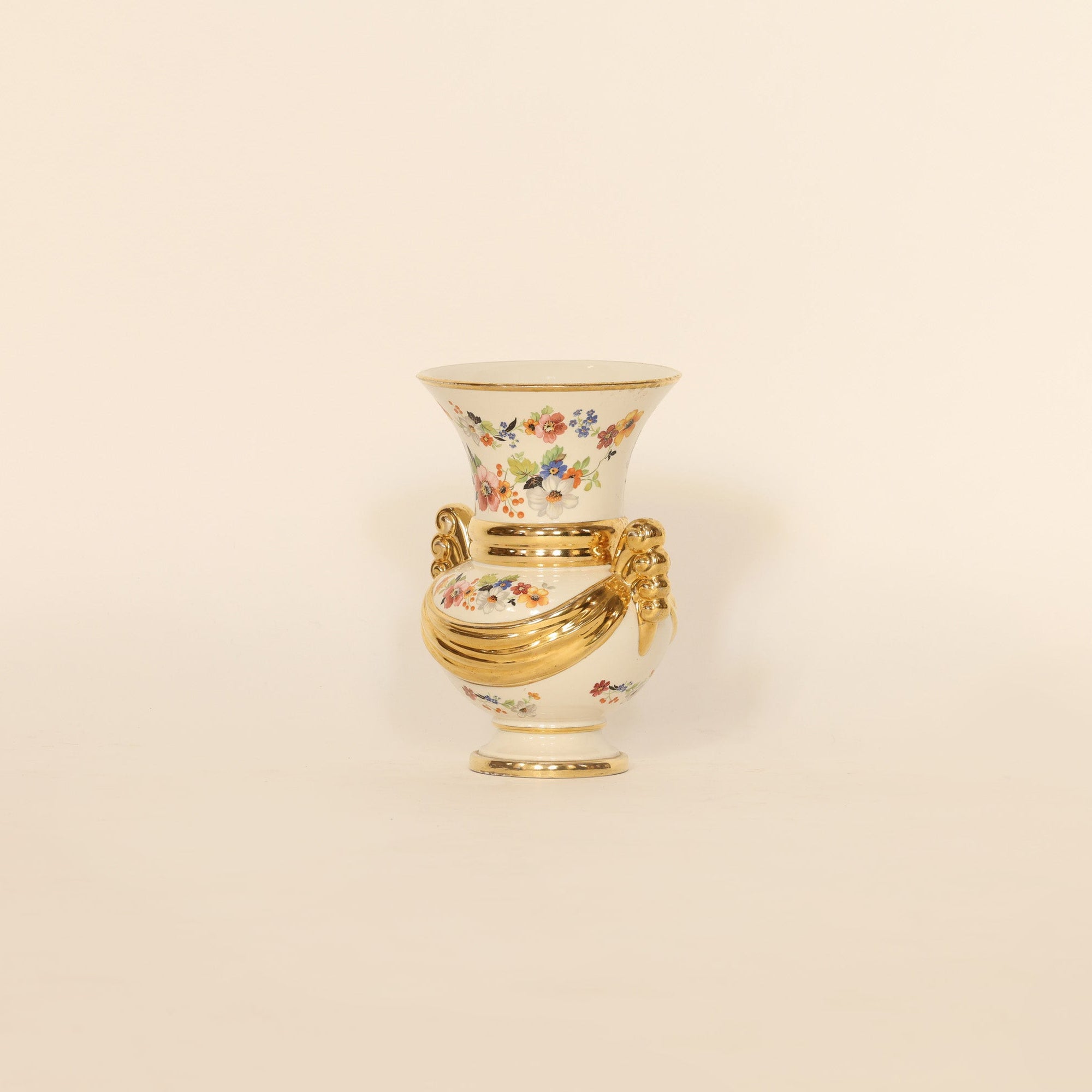 Decorative vase with floral design and gold accents on a beige background
