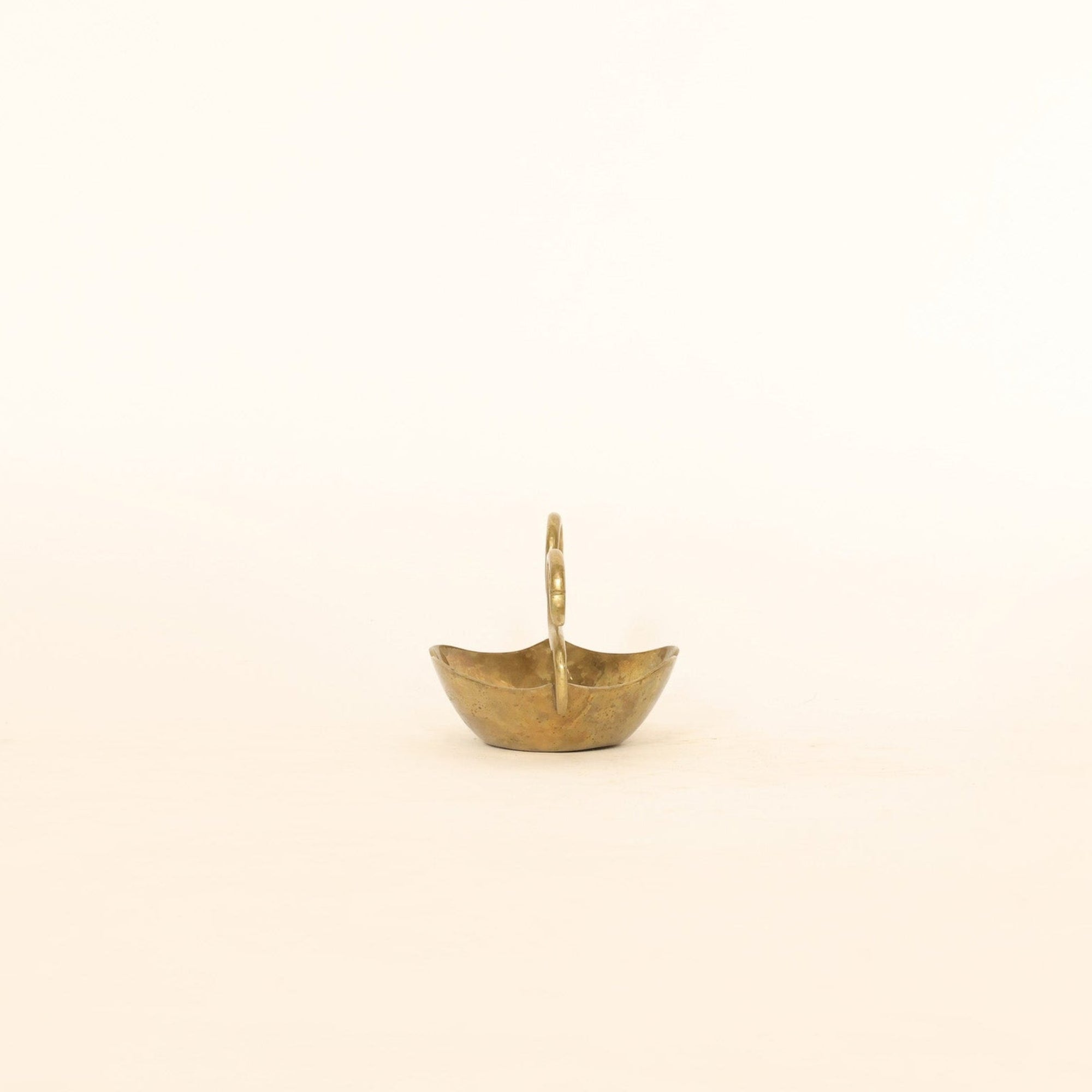 Small gold vessel on a beige background
