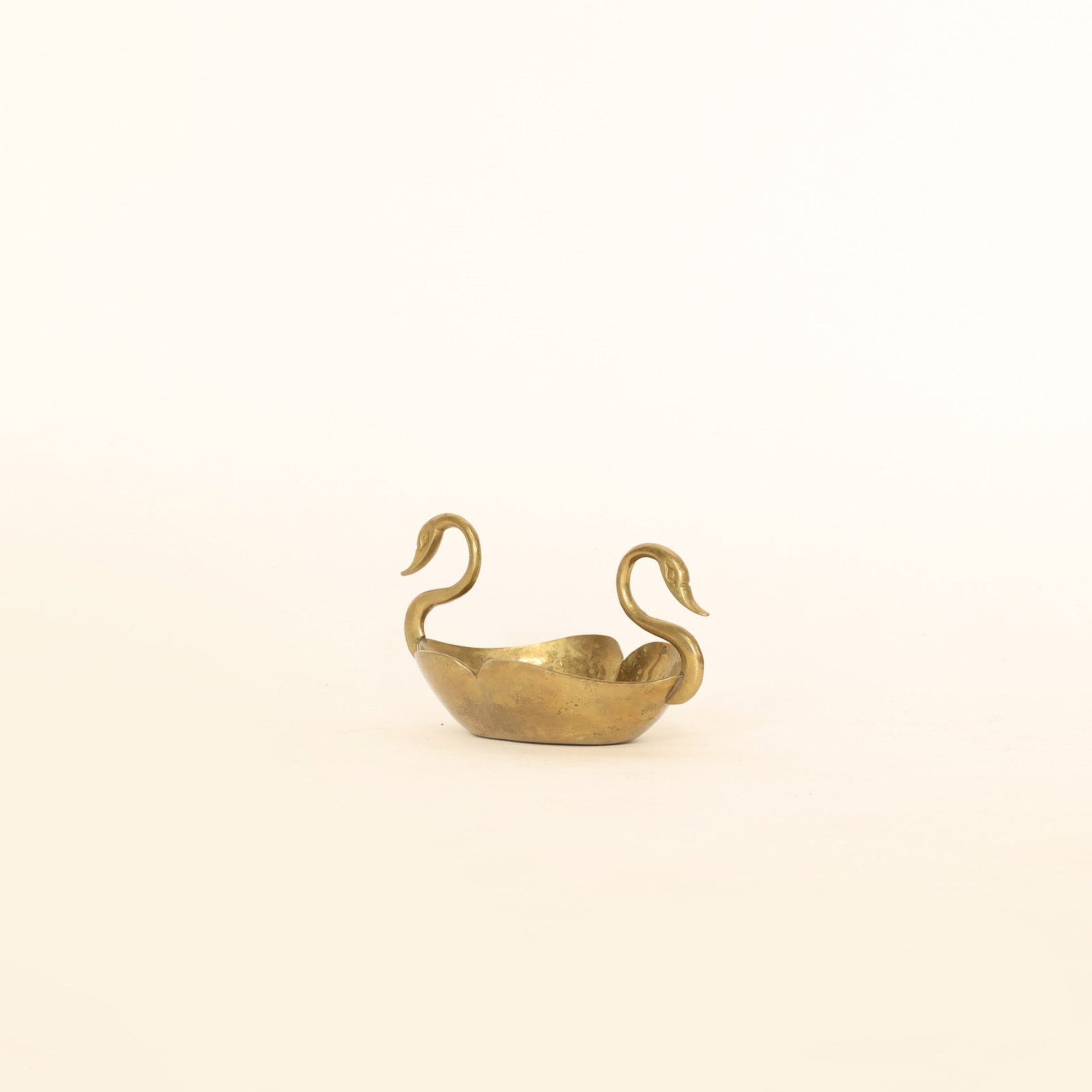Small gold swan-shaped object on a beige background